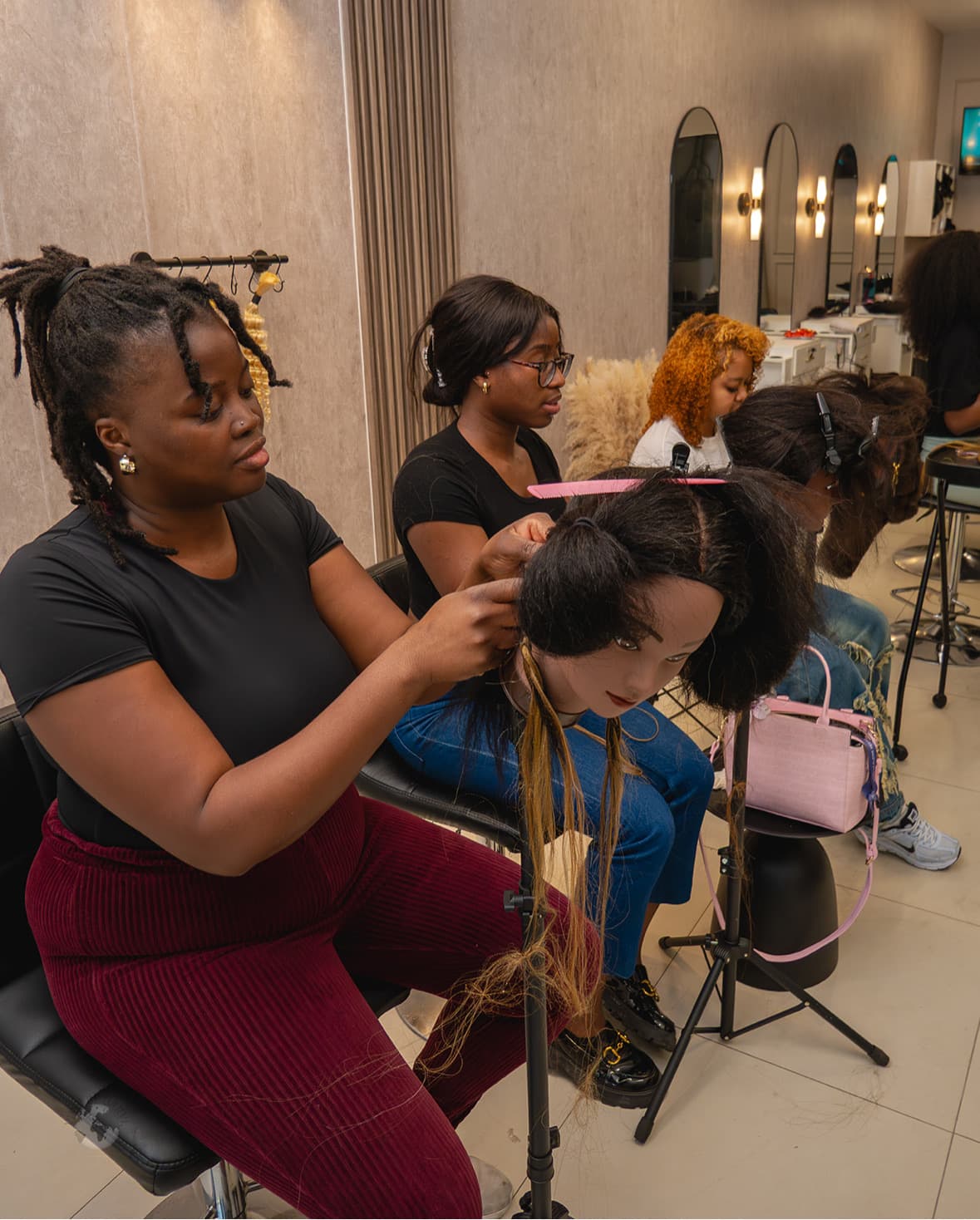 Students practising braids on mannequin heads at Nattes Hair Studio